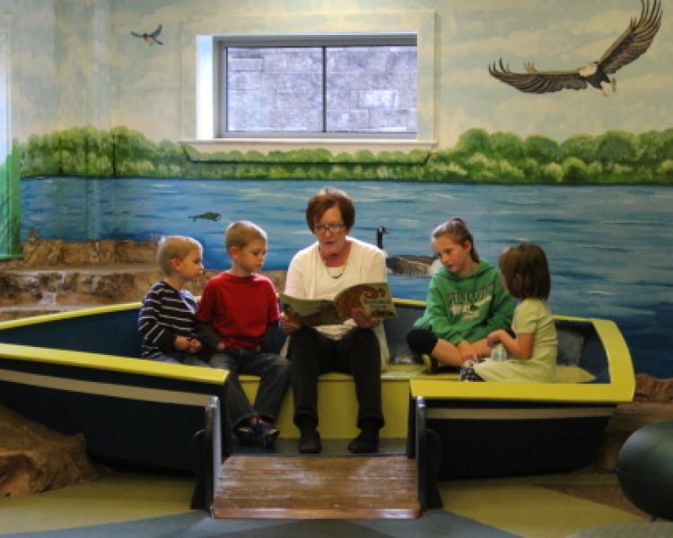 Miss Sandy reading to children in the library's kids' area.