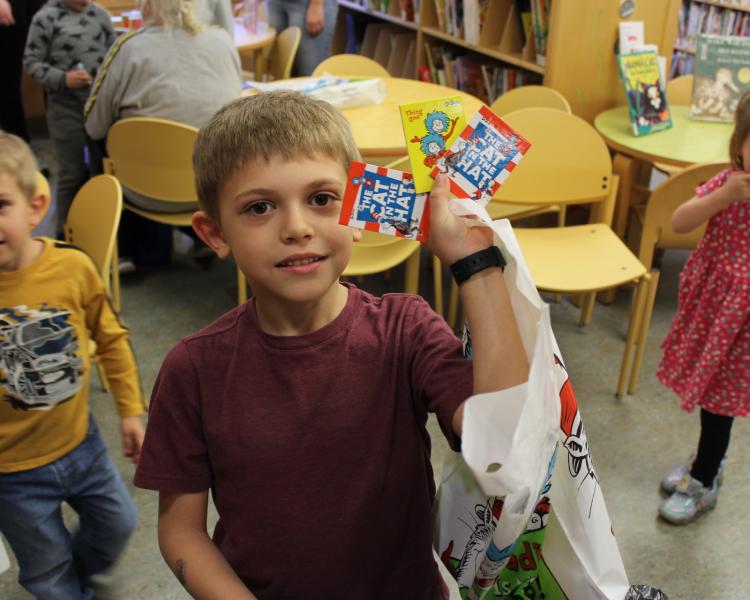 Child displaying Dr. Seuss prizes after winning game