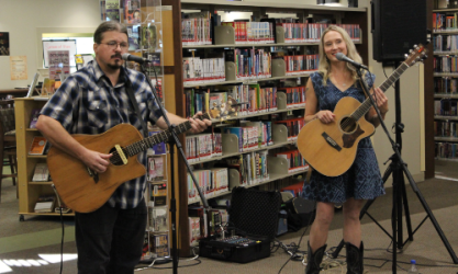 Musicians Angela Easterling and Brandon Turner playing guitar and singing in the library